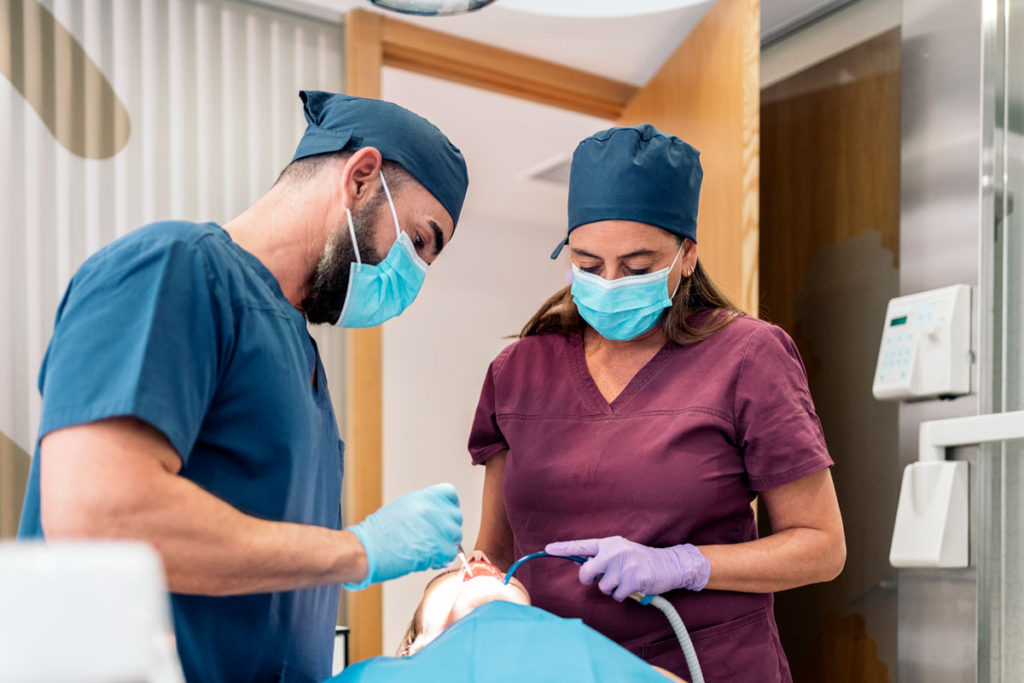 medic dentist si asistenta in timpul unei interventii de obturatie de canal