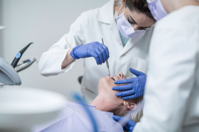 dentist examineaza pacienta cu oglinda orala